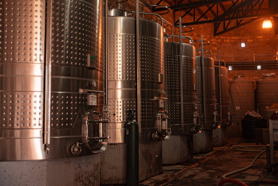Row of stainless steel tanks in an industrial plant showcasing modern production technology.