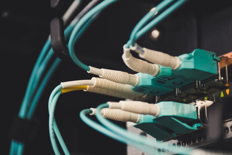 Detailed view of fiber optic cables and ports in a server room, showcasing connectivity. Detailed view of fiber optic cables and ports in a server room, showcasing connectivity.