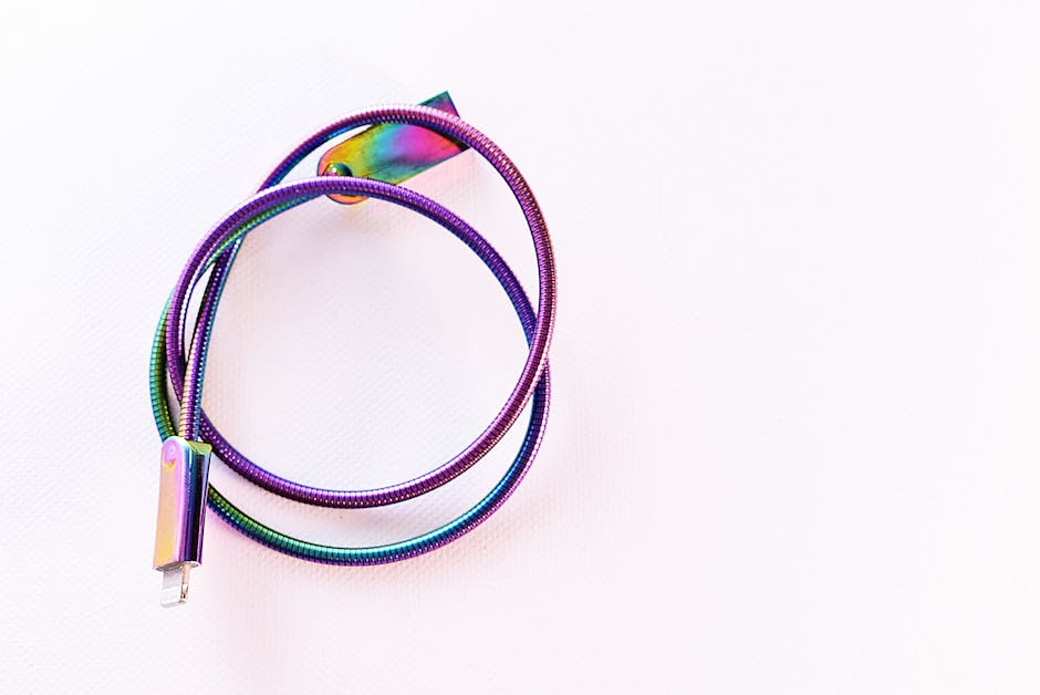 A vibrant, rainbow-colored USB cable coiled on a bright white surface.