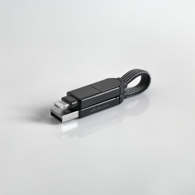 Minimalist photo of a sleek black USB flash drive with a braided loop against a white background. Minimalist photo of a sleek black USB flash drive with a braided loop against a white background.