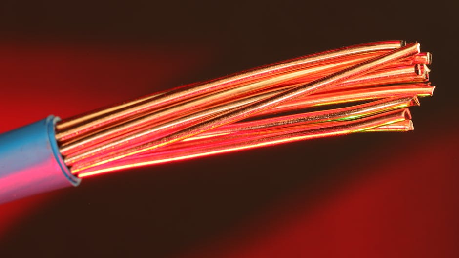 Detailed image of copper wires illuminated by red light, highlighting texture and color. Detailed image of copper wires illuminated by red light, highlighting texture and color.