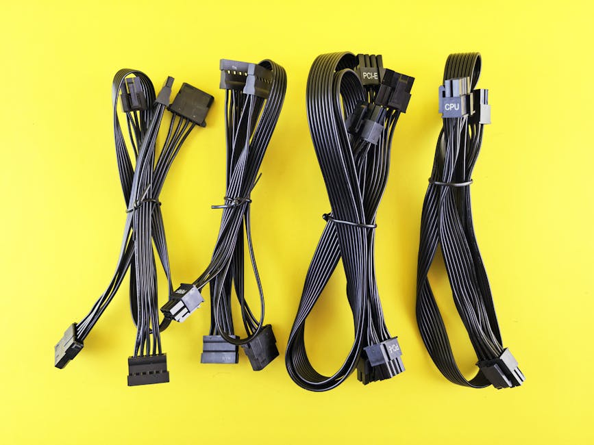 A set of black power and data cables neatly arranged on a vivid yellow background.