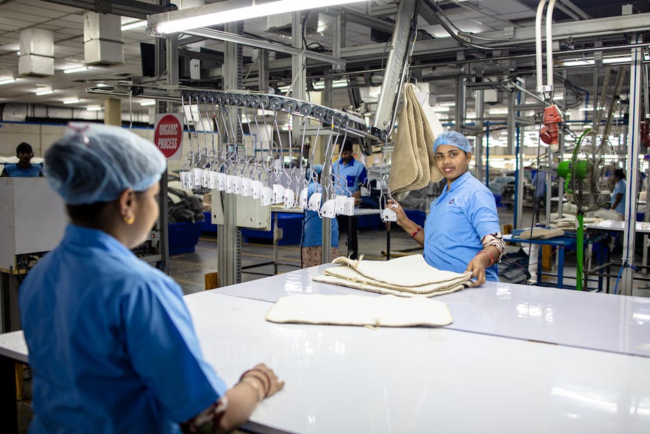 Workers organize fabrics in a textile factory using an automated system.