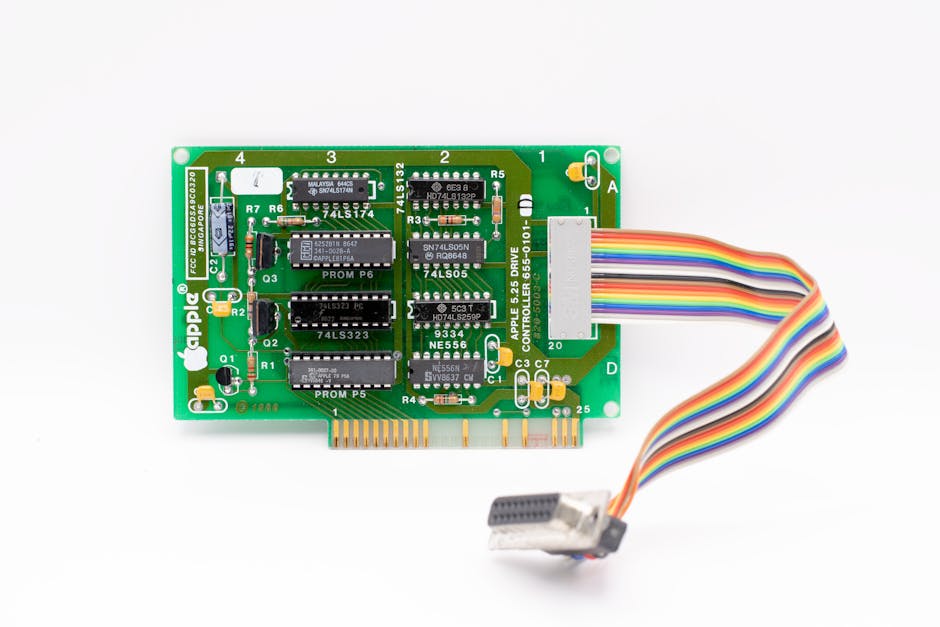 Primer plano de una placa de circuito de Apple vintage con un cable plano de colores sobre un fondo blanco.