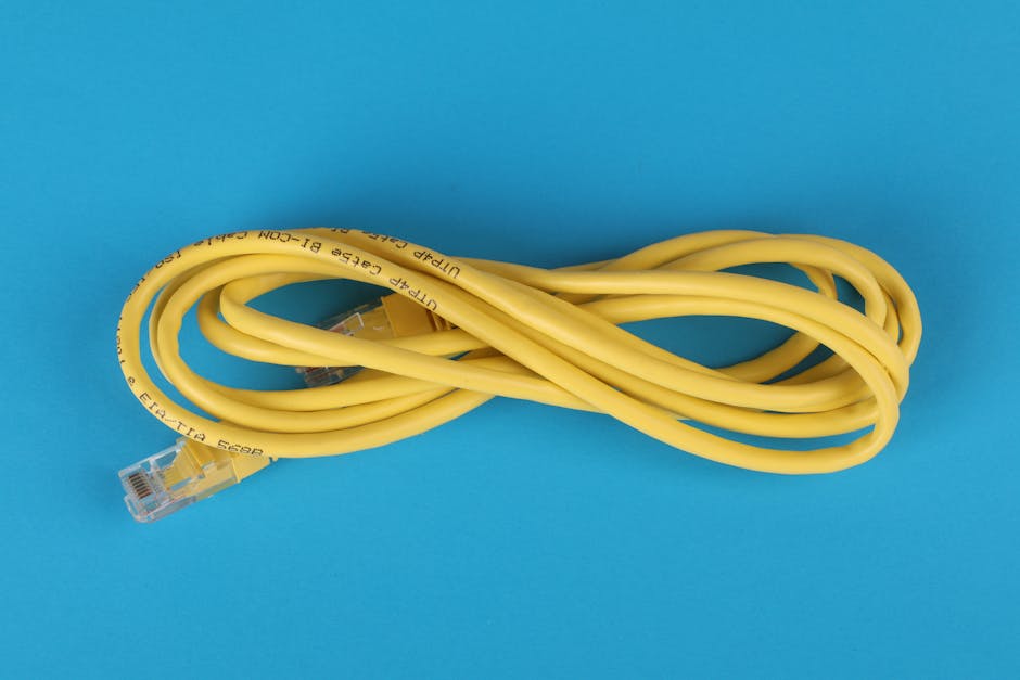 High-angle view of a yellow ethernet cable on a bright blue background. High-angle view of a yellow ethernet cable on a bright blue background.