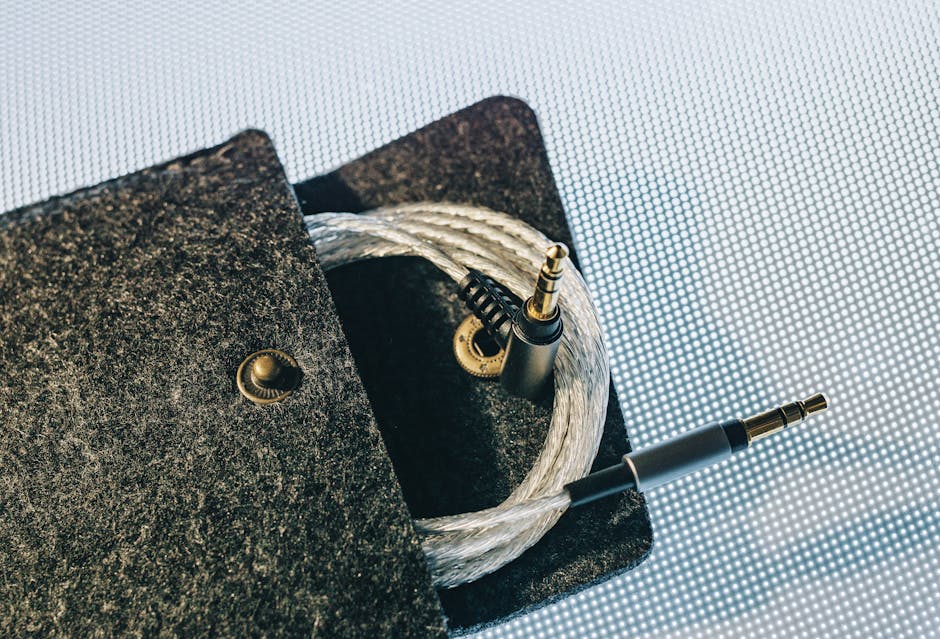 Detailed view of an audio cable coiled inside a soft felt pouch on a textured surface. Detailed view of an audio cable coiled inside a soft felt pouch on a textured surface.