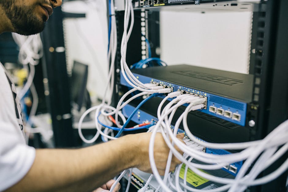 An IT professional configuring network cables in a server rack, focusing on Ethernet connections. An IT professional configuring network cables in a server rack, focusing on Ethernet connections.