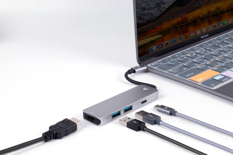 Close-up view of a USB hub connected to a laptop, showcasing various ports and cables on a white surface. Close-up view of a USB hub connected to a laptop, showcasing various ports and cables on a white surface.
