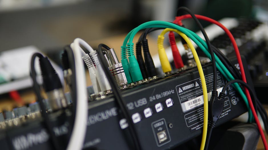 A detailed close-up image of multiple audio cables connected to a sound mixer, showcasing technology setup.
