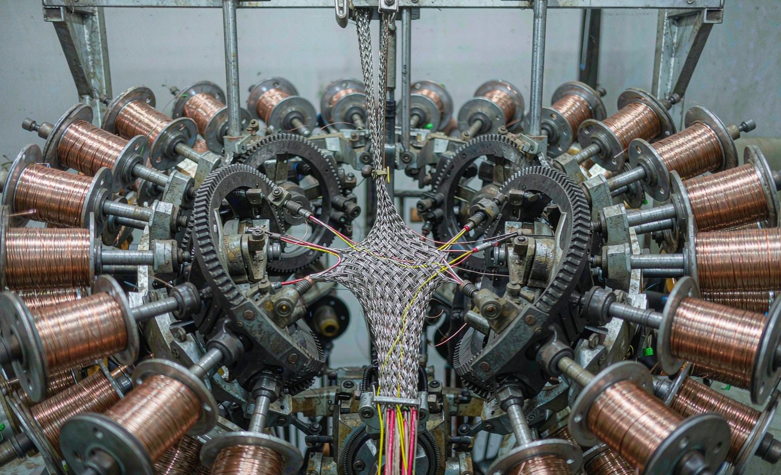 Cable braiding machine weaving a copper shield around conductors